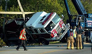Crane assists in up-righting a truck using large straps.