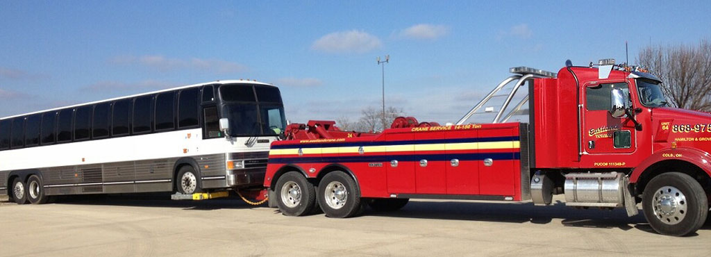 Eastland Towing red heavy duty wrecker with under reach safely towing a large tour bus.